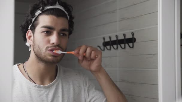Sakallı adam banyoda aynanın önünde dişlerini fırçalıyor. - Video, Çekim