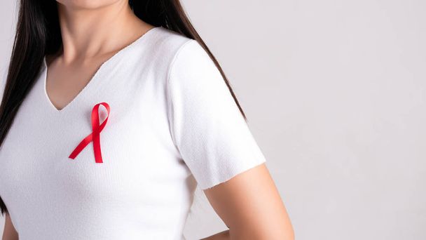 Zbliżenie czerwonej odznaki na kobiecej klatce piersiowej, by wesprzeć Dzień AIDS. Koncepcja opieki zdrowotnej, medycyny i świadomości AIDS. - Zdjęcie, obraz