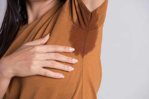 Close-up asian woman with hyperhidrosis sweating. Young asia woman with sweat stain on her clothes against grey background. Healthcare concept. - Foto, Imagem