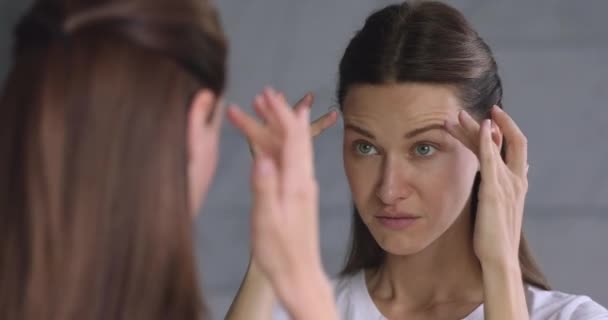 Worried 30s woman looking in mirror stressed about facial wrinkles - Footage, Video