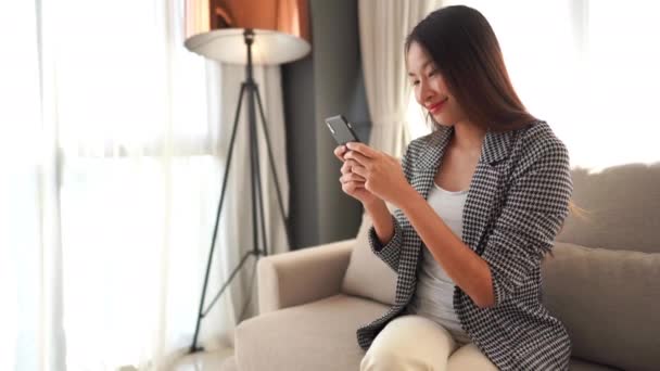 footage of beautiful asian woman using smartphone at home - Felvétel, videó