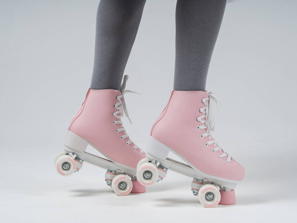 Vertical side view female legs in a gray tights and retro rollers shoes. Cropped body, stands on toes and slows down with rollers - Foto, Imagem