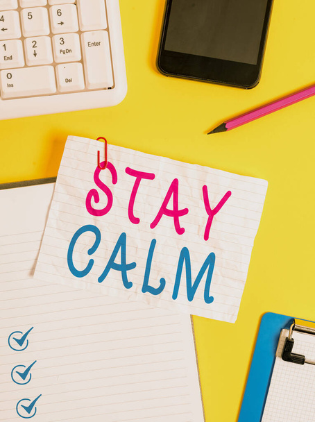 Writing note showing Stay Calm. Business photo showcasing Maintain in a state of motion smoothly even under pressure Crumpled white paper on table paper clips clock mobile and pc keyboard. - Photo, Image