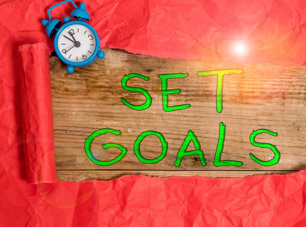 Writing note showing Set Goals. Business photo showcasing Defining or achieving something in the future based on plan Alarm clock and torn cardboard on a wooden classic table backdrop. - Photo, Image