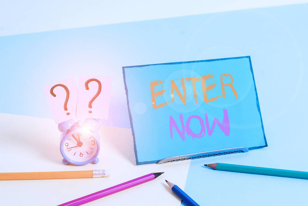Writing note showing Enter Now. Business photo showcasing come or go into a particular place To be included in a competition Mini size alarm clock beside stationary on pastel backdrop. - Photo, Image
