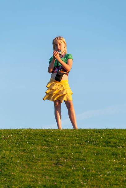 Jeune fille debout sur une colline et vérifier sa caméra avec le ciel bleu en arrière-plan
 - Photo, image