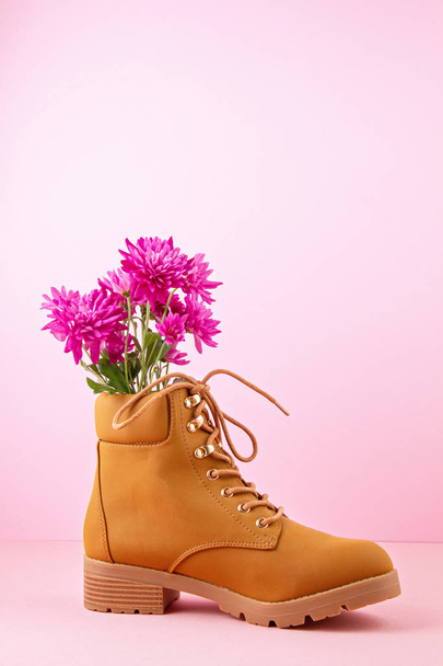 Turistika boty s růžovými květy uvnitř přes růžové pastelové pozadí. - Fotografie, Obrázek