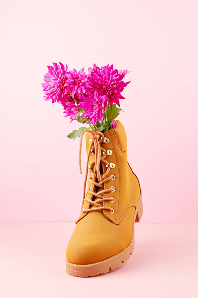 Hiking boots with pink flowers inside over the pink pastel backg - Photo, Image