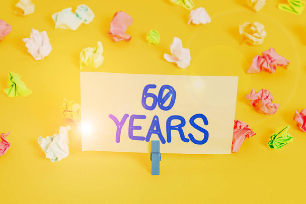 Handwriting text writing 60 Years. Concept meaning It is the onset of a golden era Commemorating a special day Colored crumpled papers empty reminder white floor background clothespin. - Photo, Image
