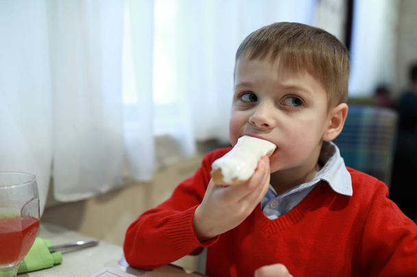 Kid eating vanilla eclair - 写真・画像