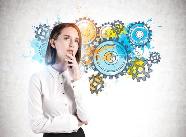 Thoughtful young business woman, cogs and gears - 写真・画像