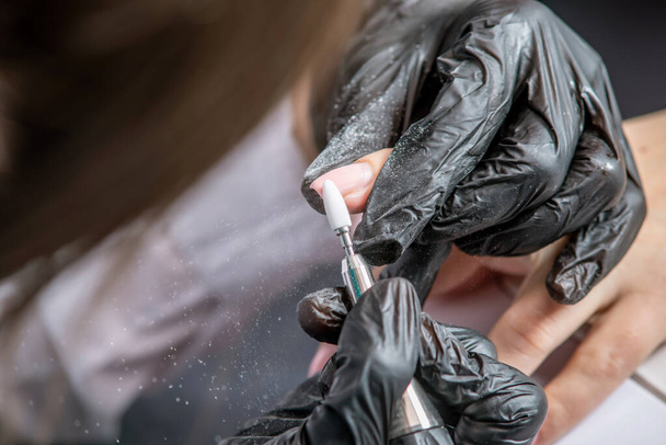 Nainen manikyyri master tekee laitteisto manikyyri mustat käsineet poistamalla vanha pinnoite geeli Puolan salonki - Valokuva, kuva