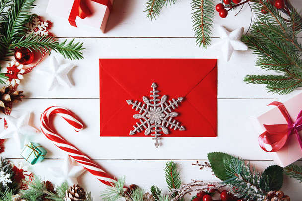 Christmas composition. Christmas gift, , pine cones, fir branches on wooden white background. Empty christmas card with envelope  Flat lay, top view, copy space. New Year. - Fotografie, Obrázek