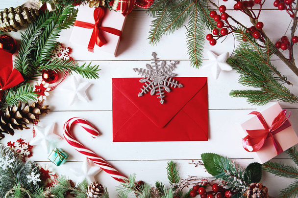 Christmas composition. Christmas gift, , pine cones, fir branches on wooden white background. Empty christmas card with envelope  Flat lay, top view, copy space. New Year. - Φωτογραφία, εικόνα