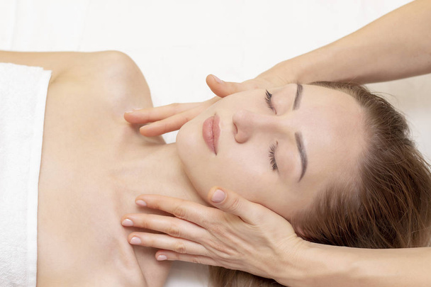 Young woman enjoying massage in spa salon. Face massage. Closeup of young woman getting spa massage treatment at beauty spa salon.Spa skin and body care. Facial beauty treatment.Cosmetology.  - Foto, Bild