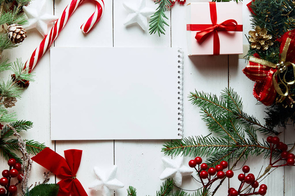 Christmas theme with blank paper on wooden white background. Christmas decoration. Creative layout made of Christmas tree branches with paper card note. Flat lay.  - Φωτογραφία, εικόνα