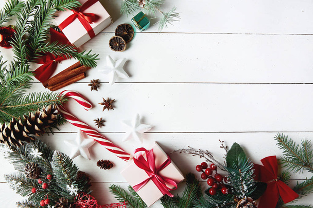 Όμορφη Χριστουγεννιάτικη σύνθεση σε λευκό φόντο με χρυσά χριστουγεννιάτικα κουτιά δώρων, χιονισμένα κλαδιά ελάτης, κώνους κωνοφόρων, διακόσμηση διακοπών και κόκκινο μούρο. Άνω όψη - Φωτογραφία, εικόνα