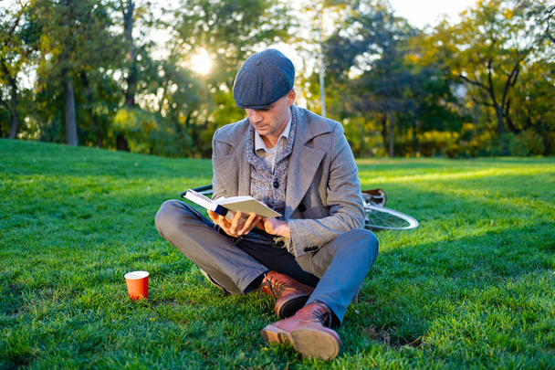 Fiatal férfi hipster retro kerékpár olvasókönyv őszi parkban - Fotó, kép