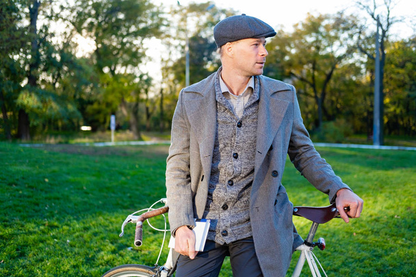 Νέοι άνδρες hipster με ρετρό ποδήλατο διαβάσει το βιβλίο στο πάρκο φθινόπωρο - Φωτογραφία, εικόνα