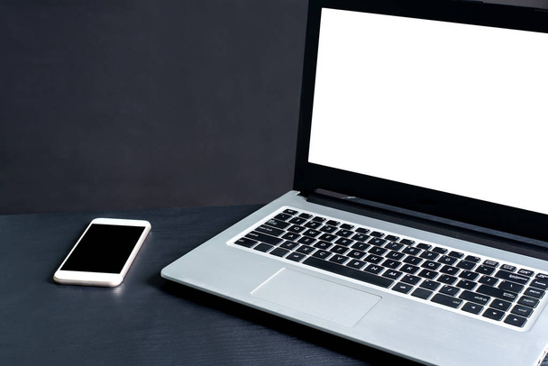 Laptop, akıllı telefon, siyah arka planlı siyah ahşap masa. - Fotoğraf, Görsel