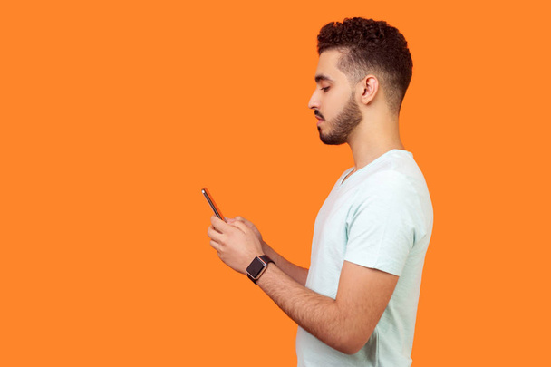 Side view of serious calm brunette man using cellphone. empty co - Foto, Imagen
