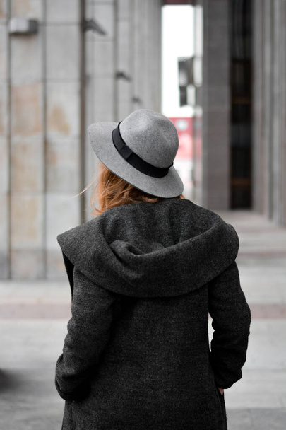 Back view of woman in a long grey and coat, wearing hat - Foto, afbeelding