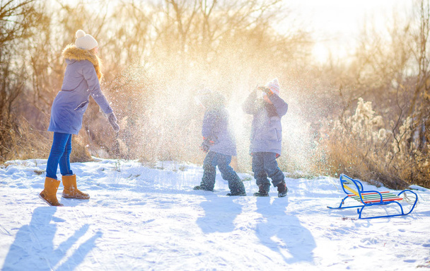 Happy children play in a snowy winter park at sunset. They play with snow and have fun. Winter fun. Holidays. - Fotoğraf, Görsel