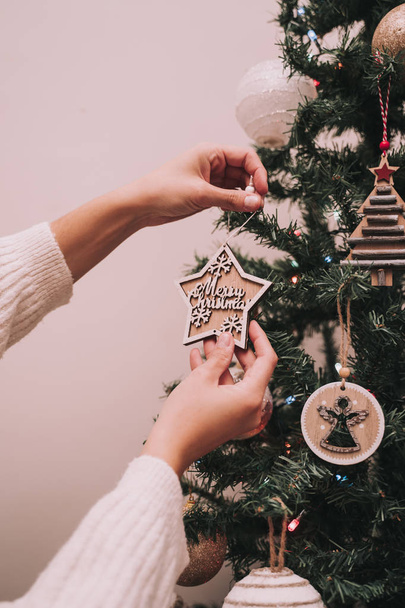 Κάποιος διακοσμεί το χριστουγεννιάτικο δέντρο. Το άτομο κρεμάει ένα χριστουγεννιάτικο αστέρι με ένα χριστουγεννιάτικο χαιρετισμό. Κοντινό πλάνο. - Φωτογραφία, εικόνα