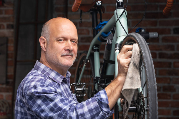 Mekaanikko tai ratsastaja puhdistaa öljyä polkupyörän pyörästä
 - Valokuva, kuva