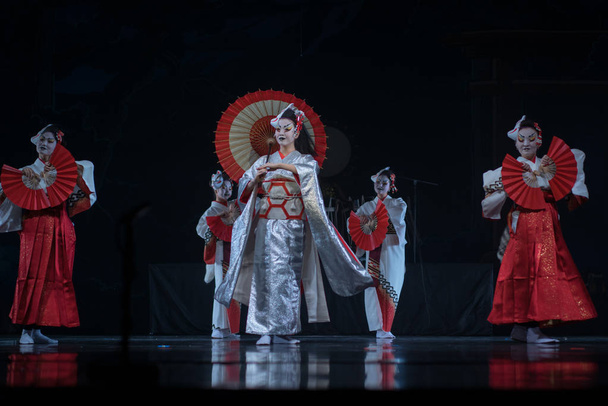 П'ять актрис в традиційних білих і червоних масках кімоно і лисиць танцюють з парасолькою і шанувальниками
. - Фото, зображення