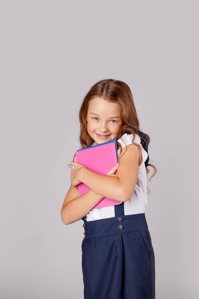 pretty schoolgirl holds a stack of notebooks and smiles - Foto, imagen