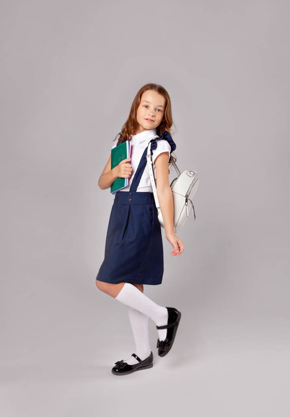 cute schoolgirl with a backpack holds notebooks - Fotó, kép