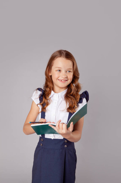 Lächelndes Mädchen schreibt etwas in ein offenes Notizbuch - Foto, Bild