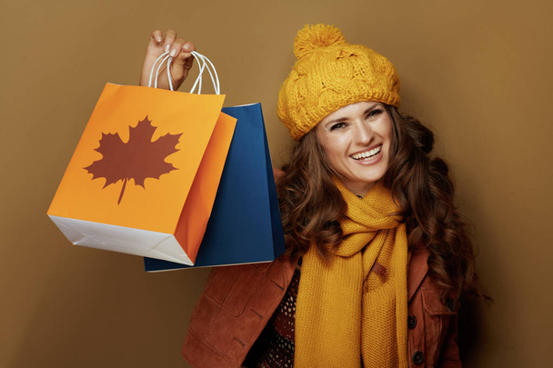 woman showing autumn shopping bags against bronze background - Foto, immagini