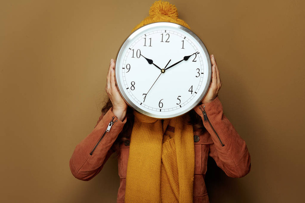woman hiding behind round clock remind about autumn time change - Photo, Image