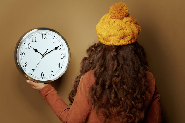 woman showing round clock remind about autumn time change - Photo, Image