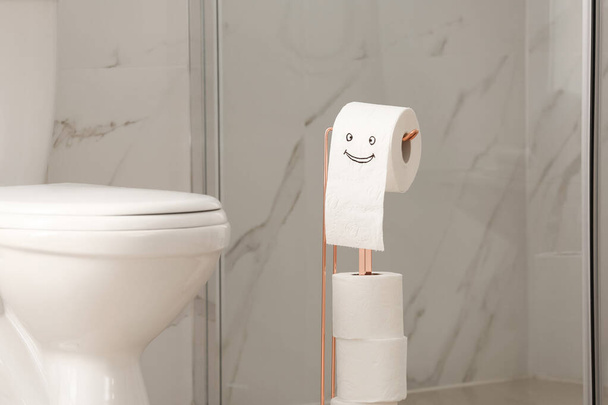 Modern toilet bowl and paper with funny face in bathroom - Fotoğraf, Görsel