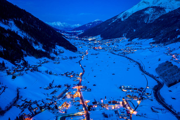Krajobraz zimowej nocy w austriackim mieście Neustift. Widok z lotu ptaka na centrum miasta i kościół. Nocne oświetlenie domów i sygnalizacja świetlna. Tyrol, Dolina Stubai - Zdjęcie, obraz