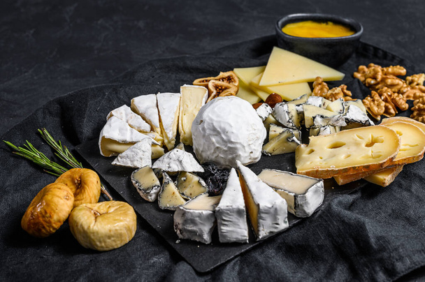 Assortment of French cheese with honey, nuts and figs on cutting board. Italian antipasto. Black background. Top view - Φωτογραφία, εικόνα