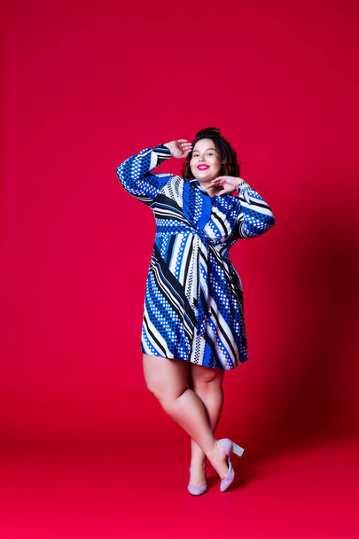 Plus size model in blue dress, fat woman on red background - Photo, Image