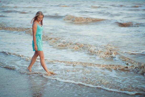 Mulher feliz bonita sorrindo e andando na costa do mar
 - Foto, Imagem