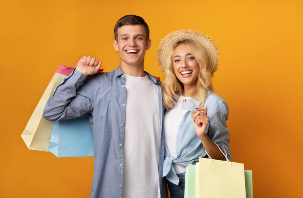 Šťastný mladý pár pózuje s nákupními taškami a kreditní kartou - Fotografie, Obrázek