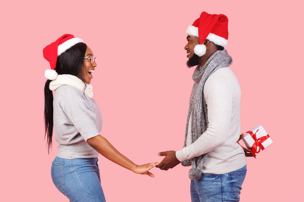 Санта-мужчина делает сюрприз, дарит рождественский подарок своей изумленной женщине
 - Фото, изображение