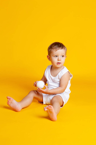 bebé de un año se sienta en una camiseta y pantalones cortos y tiene un Chris
 - Foto, Imagen