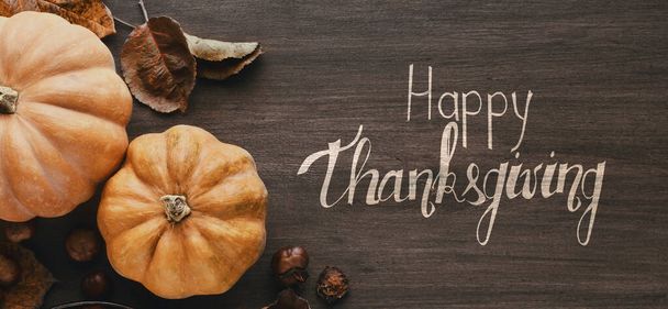 Feliz saludo de Acción de Gracias en mesa rústica con calabazas
 - Foto, imagen