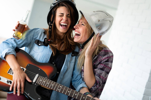 Friends at home enjoying singing and playing guitar, having fun - Фото, зображення