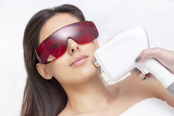 procedure of photoepilation in the beauty salon. Young Woman Receiving Epilation Laser Treatment On Face At Beauty Center Close Up - Valokuva, kuva