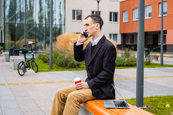 businessman work outdoors with laptop and cellphone - 写真・画像
