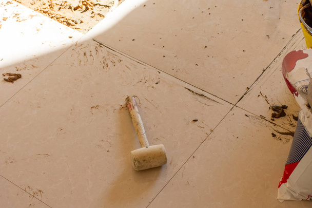 Woningrenovatie van keramische tegels op een toegangsweg. Tegels aftappen met rubberen hamer a Diy en egaliseertegels met mortel en cement. - Foto, afbeelding