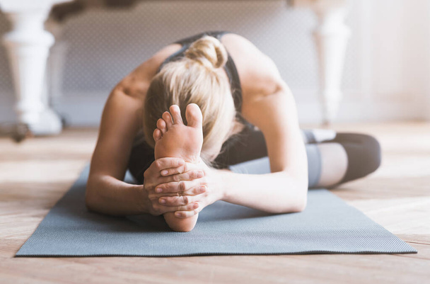 Sporty girl stretching, touching her knees with forehead - Valokuva, kuva